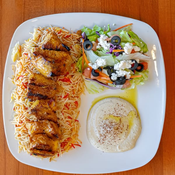 Halal Bites' chicken and rice platter with a side salad and hummus on a white plate.