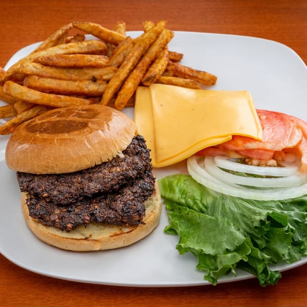 Halal Bites' fast-food burger with two patties, fries, cheese, lettuce, tomato, and onion.