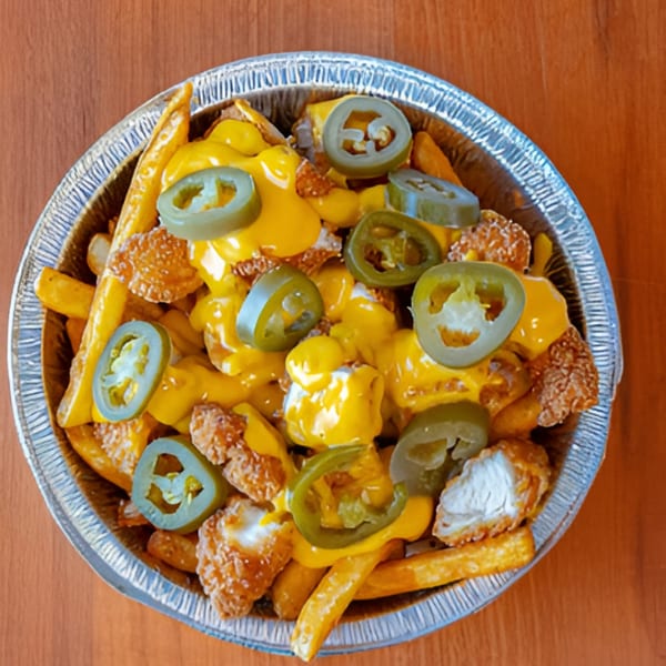 Halal Bites' cheesy fries topped with crispy chicken pieces and sliced jalapeños in a foil container.