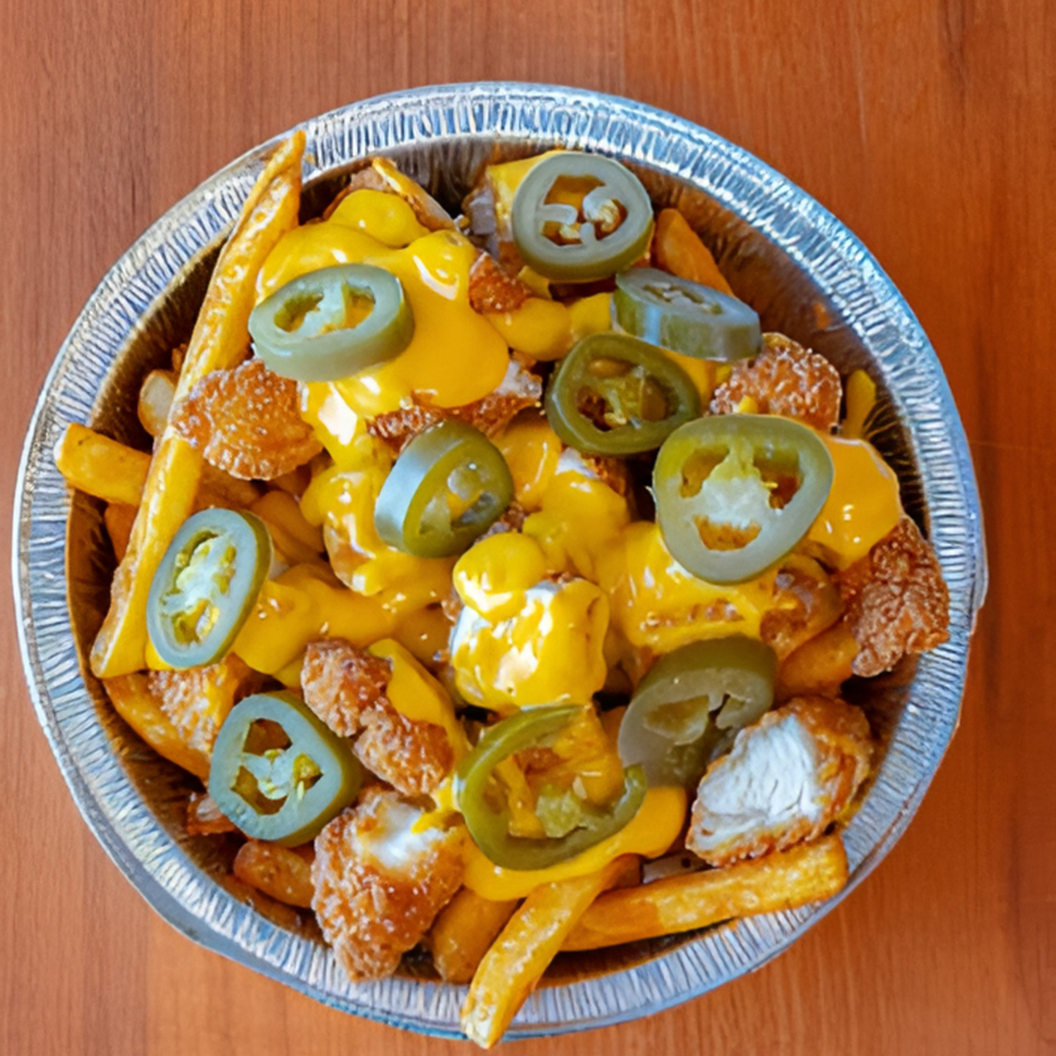 Halal Bites' cheesy fries topped with crispy chicken pieces and sliced jalapeños in a foil container.