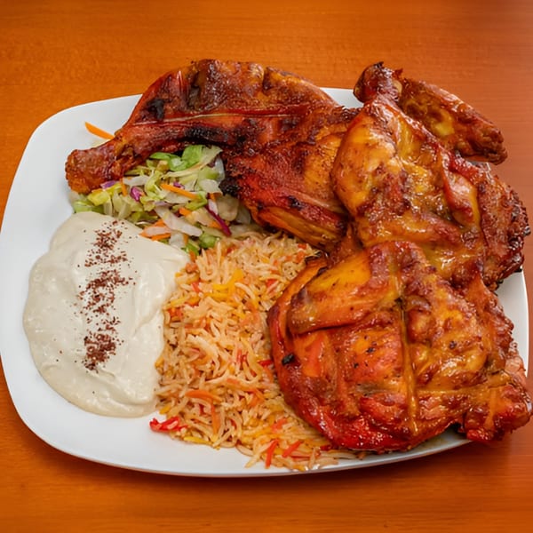 Halal Bites' grilled chicken with rice, salad, and white sauce on a white plate.