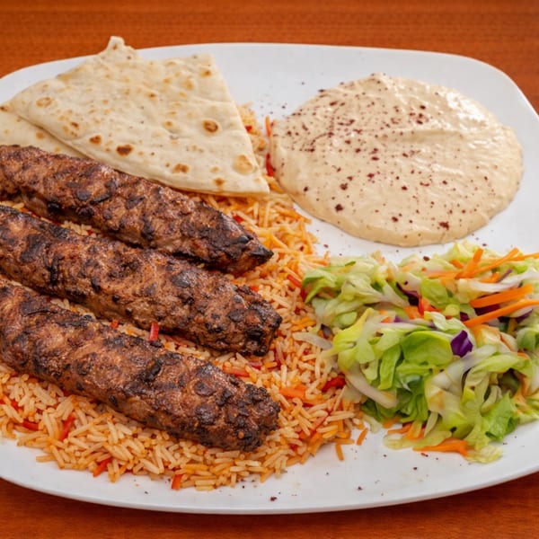 Halal Bites' platter with three grilled kebabs, rice, salad, hummus, and pita bread.