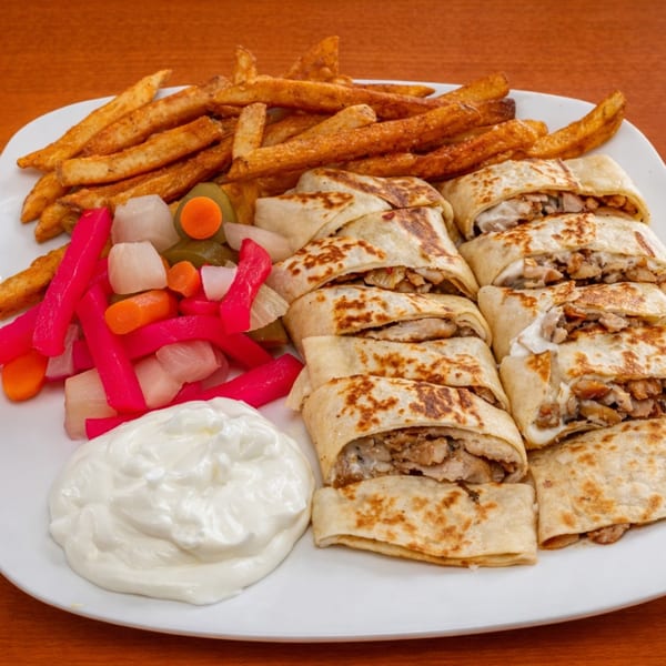 Halal Bites chicken shawarma wraps, fries, pickled vegetables, and white sauce on a plate.
